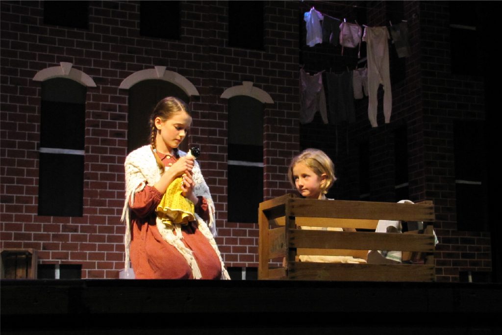 Two young actresses on stage performing in a play about George Muller
