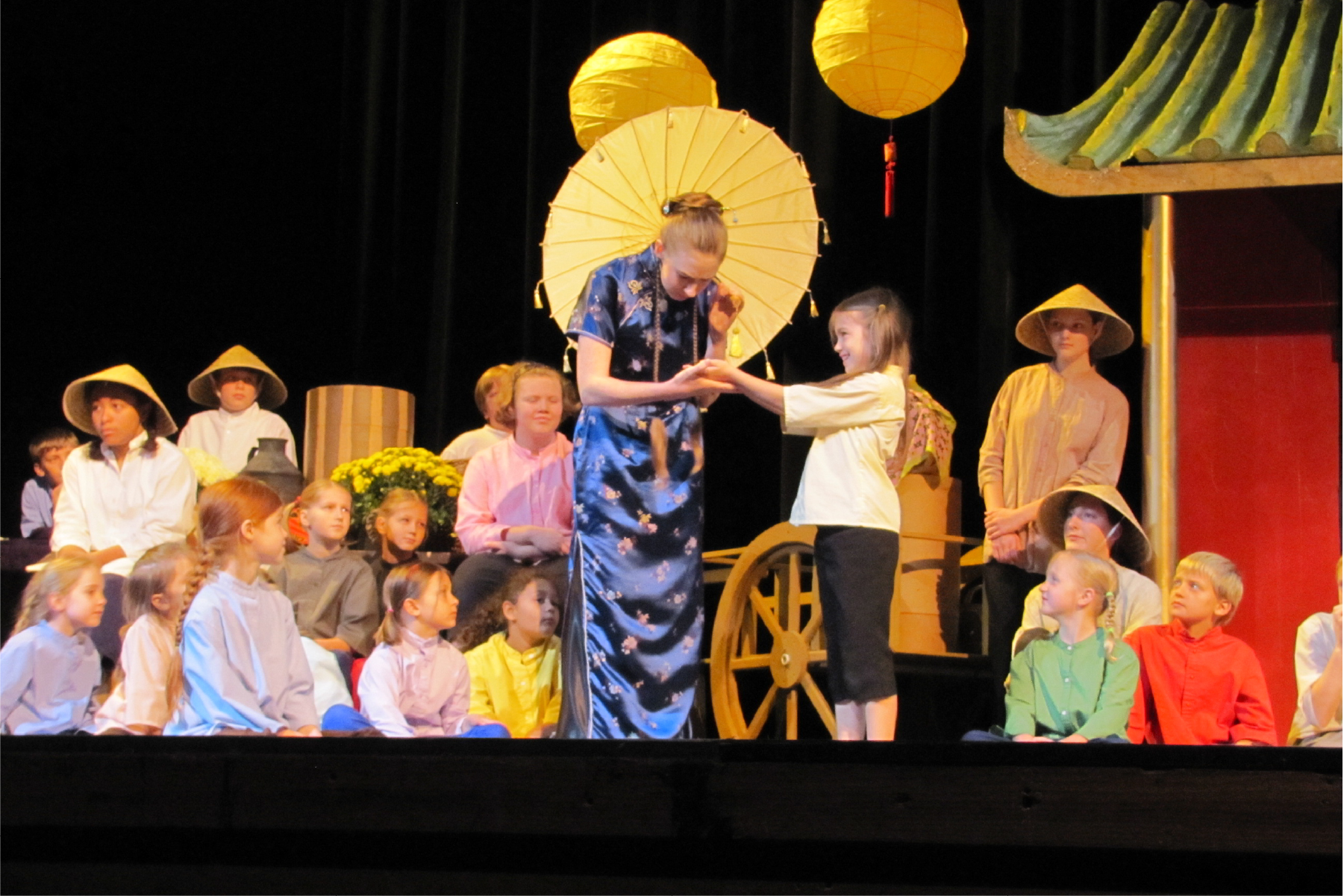 Several young actors and actresses dressed in period Chinese clothing on stage portraying characters in a play about missionary Gladys Aylward.