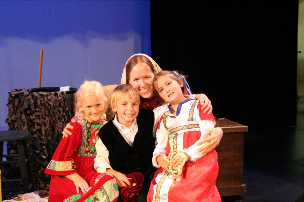 Director, Mev McCurdy with three young cast members in costume after a play performance