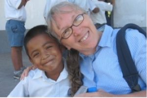 An older American woman hugging a young Belize student with big smiles.