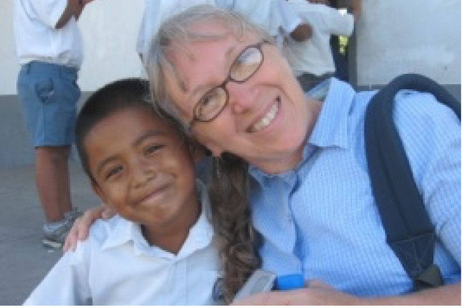 An older American woman hugging a young Belize student with big smiles.