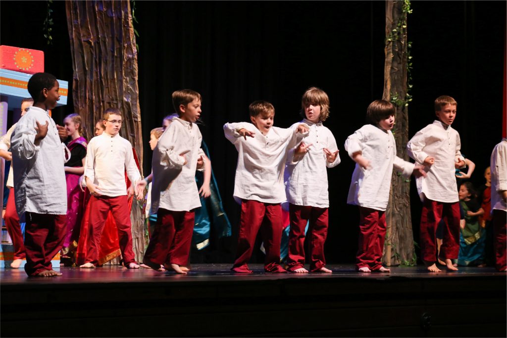 Young male actors dressed in red and white period clothing performing